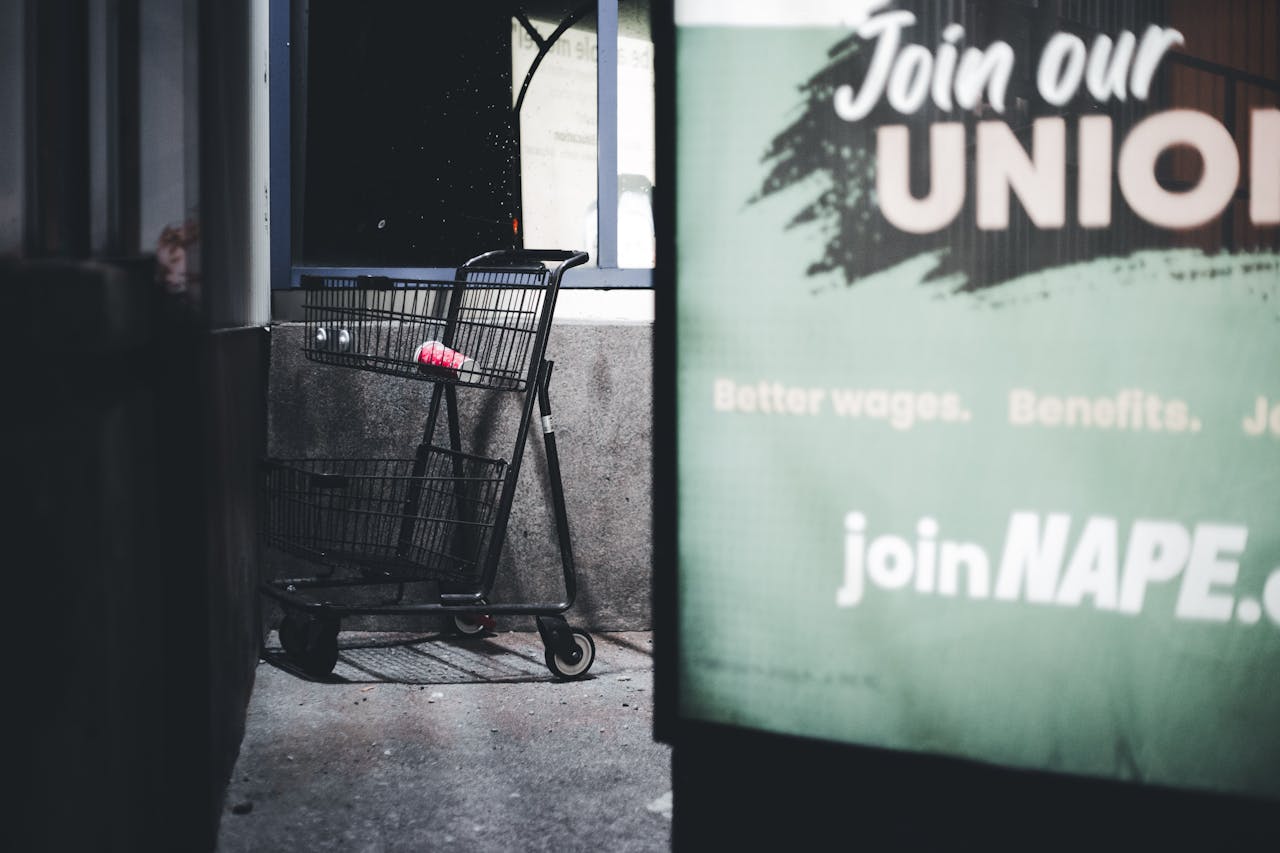 hero-img Dramatic urban scene featuring an empty shopping cart and a union sign at night.
